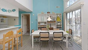 Una cucina moderna con un piano di lavoro bianco, sedie in legno e una parete blu a contrasto.