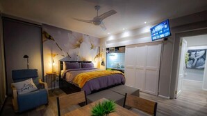 A modern bedroom with a bed, a desk, a chair, a television, and a wardrobe. - The Butterfly Villa (Pringle Bay)