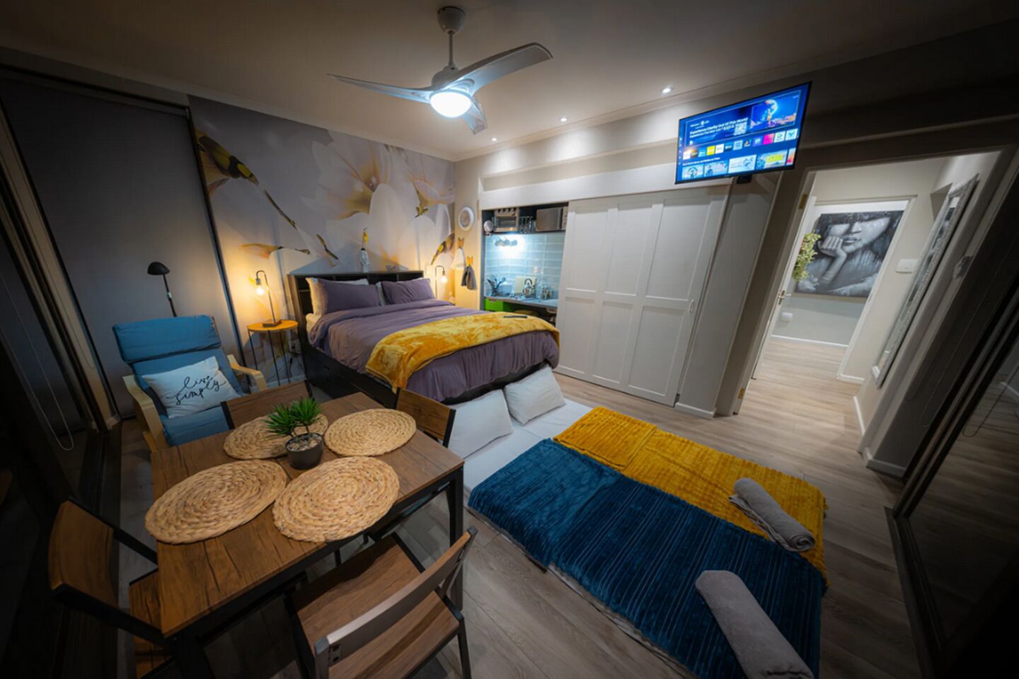 Una habitación de hotel moderna con cama, televisión, zona de comedor y baño.