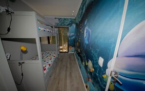 Une chambre avec des lits superposés et une fresque murale représentant un paysage sous-marin.