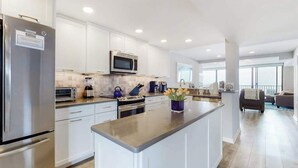 Una cocina moderna con armarios blancos, electrodomésticos de acero inoxidable y una isla central.