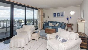 Un balcon avec vue sur la mer, un ensemble de meubles de salon blancs et un ensemble de meubles de salon bleus.