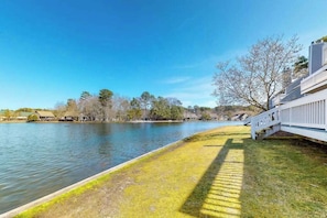 A waterfront property with a grassy area, a white fence, and trees in the background. - Sea Colony Ocean 2nd floor condo w/ basketball court, pool, and balcony (Bethany Beach)