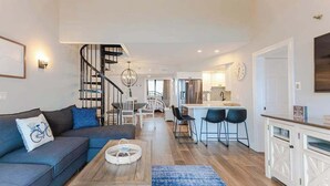 Un soggiorno moderno con divano, tavolino e una scala che conduce verso una zona cucina.