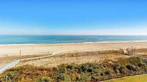 A beach with a clear sky, a sandy shore, and a fenced area with vegetation. - Sea Colony Ocean 3rd floor condo w/ pool, tennis court, and elevator (Bethany Beach)