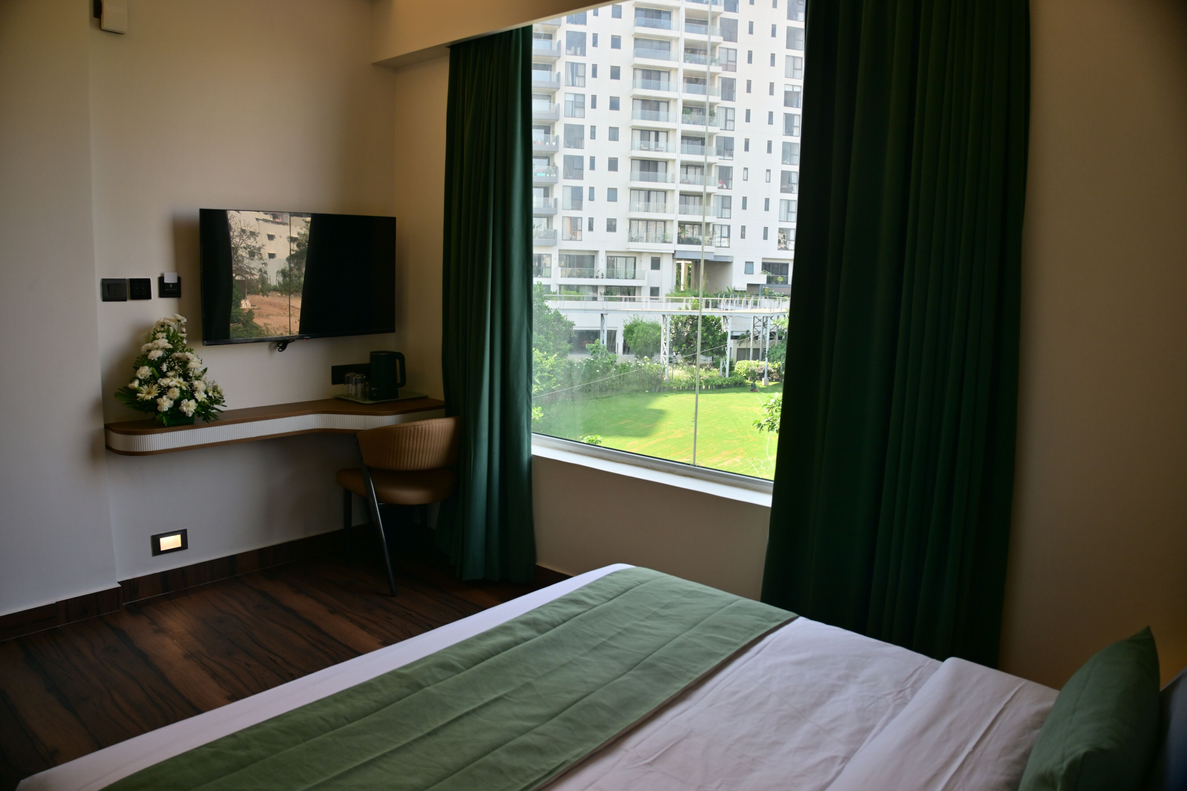 A hotel room with a bed, a desk, a TV, and a window with curtains.