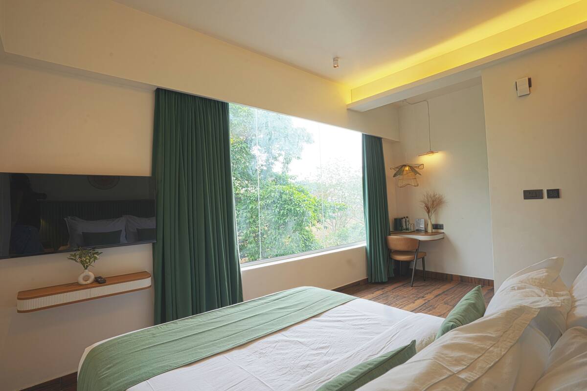 Ein modernes Hotelzimmer mit einem großen Bett, einem Schreibtisch, einem Stuhl und einem Fenster mit Vorhängen.