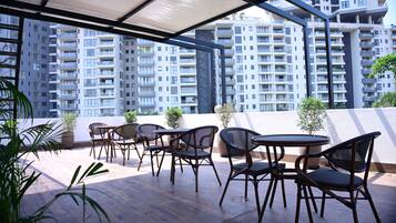 Terraço no telhado com área de estar externa e vista para edifícios altos.