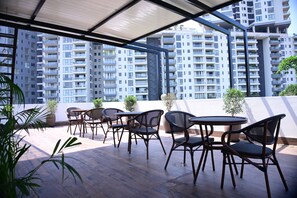 Terraço no telhado com área de estar externa e vista para edifícios altos.