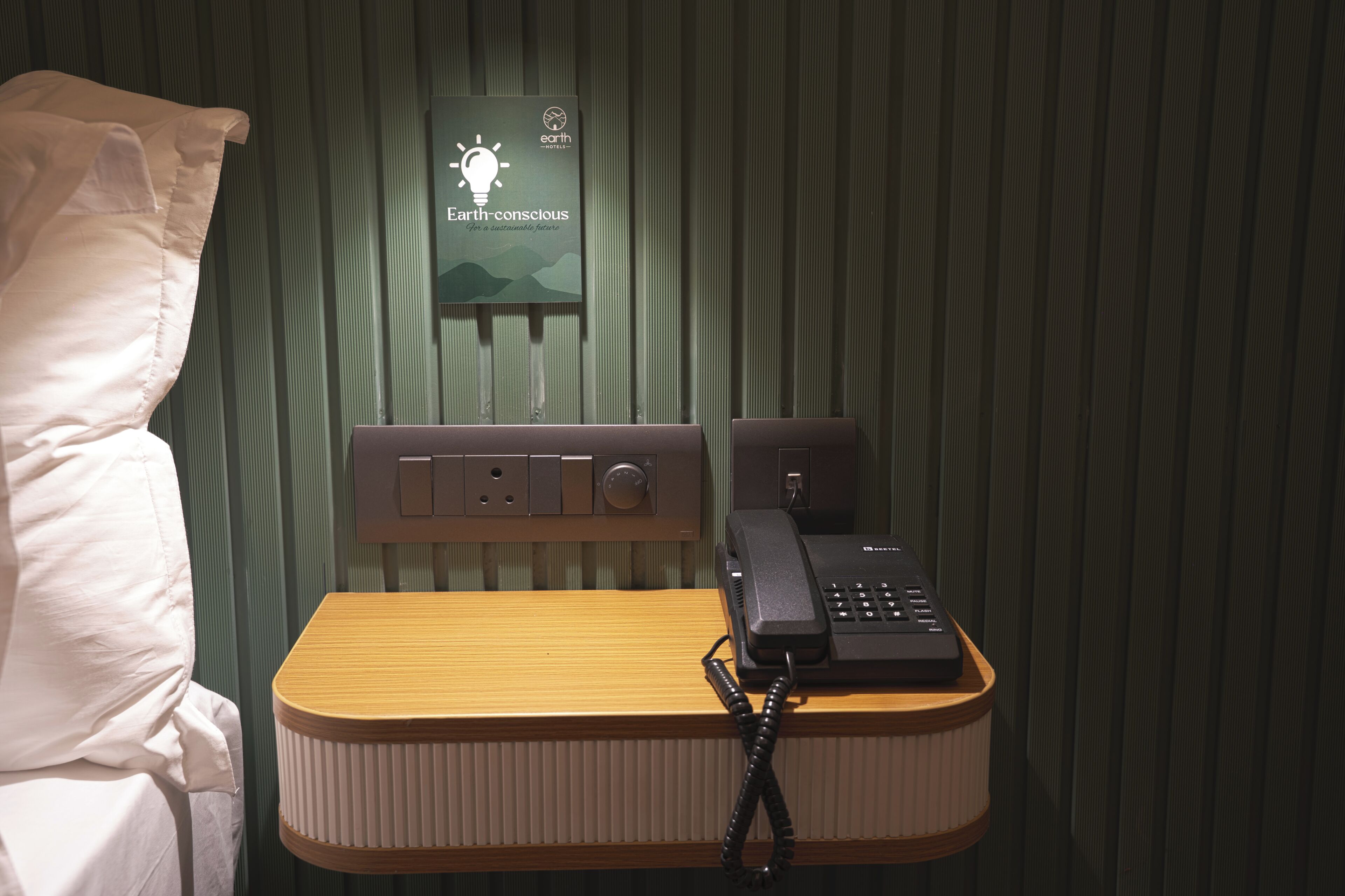 Une chambre d’hôtel avec un lit, une table de chevet avec un téléphone et un panneau fixé au mur.