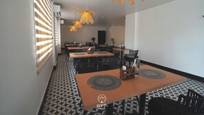 A hotel dining area with multiple tables and chairs, patterned flooring, and pendant lighting. - Earth Hotels Hebbal (Bengaluru)