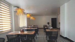 A dining area with tables and chairs, pendant lighting, and a patterned floor. - Earth Hotels Hebbal (Bengaluru)