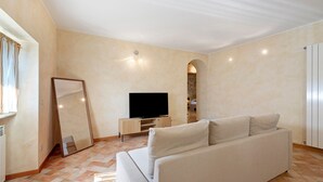 A living room with a sofa, a television, and a mirror.