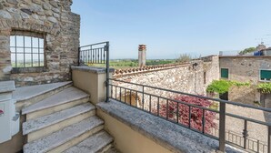 A stone building with a staircase leading to a balcony with a metal railing.