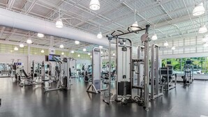 A spacious gym with various exercise machines, a high ceiling with industrial lighting, and large windows. - Sea Colony Ocean 6th-floor condo wit balcony, tennis court, & basketball court (Bethany Beach)