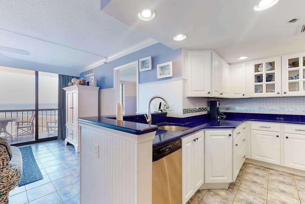 A modern kitchen with white cabinets, a blue countertop, and a dishwasher.