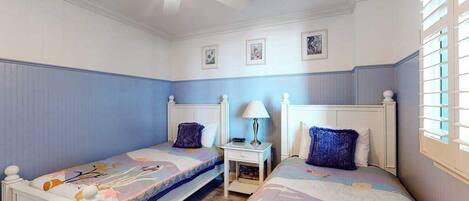 A bedroom with two beds, a ceiling fan, a nightstand, and a window with blinds.
