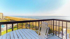 A balcony with a view of the beach and ocean, a white chair, and a table. - Sea Colony Ocean 6th-floor condo wit balcony, tennis court, & basketball court (Bethany Beach)