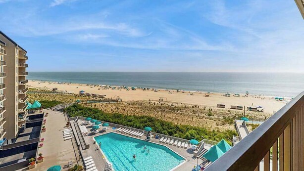 A poolside view with a beach and ocean in the background. - Sea Colony oceanfront 7th floor condo with free WiFi and elevator (Bethany Beach)