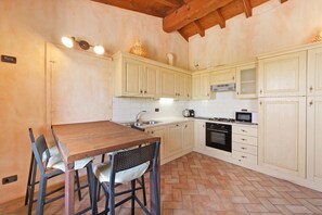 Eine Küche mit Holzausbau, einer gefliesten Spritzschutzwand, einem Holzespeisetisch mit Stühlen und einem Parkettboden mit Zickzackmuster.