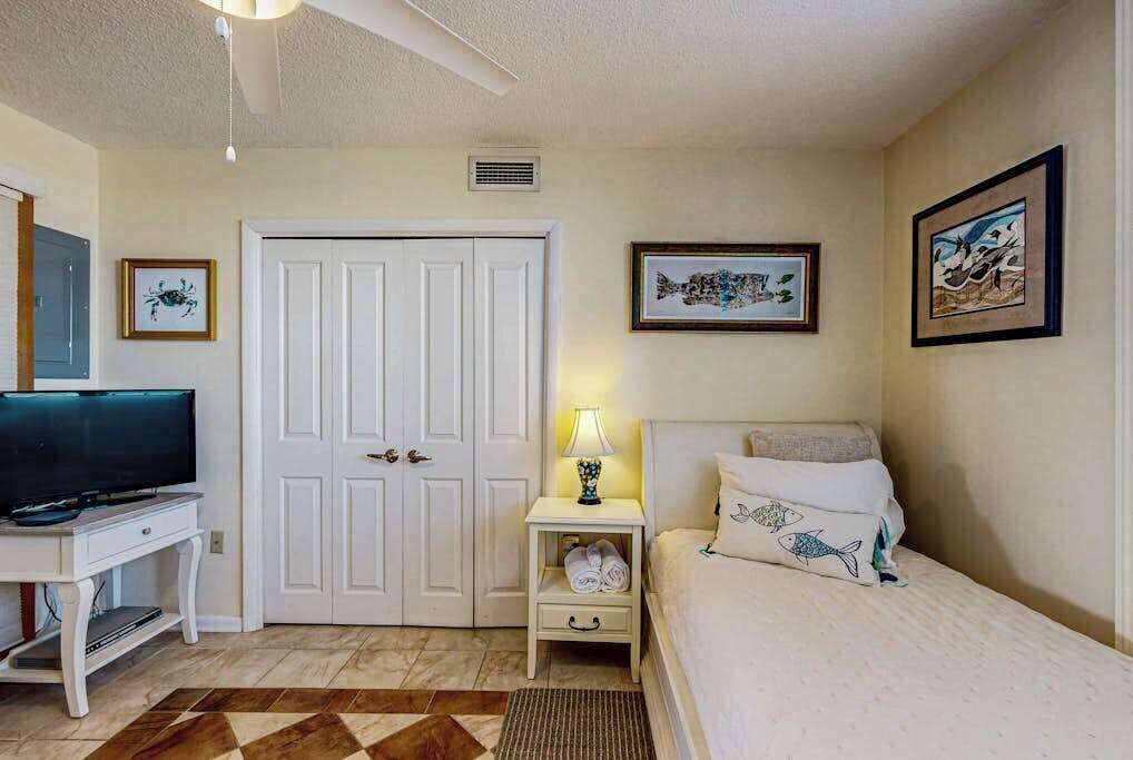 A bedroom with a bed, a TV, a desk, and a door.