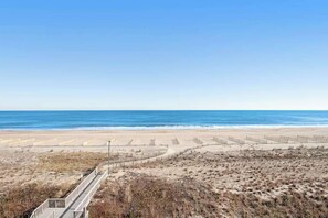 A beach with a boardwalk leading to the ocean, sandy dunes, and a clear sky. - Oceanfront fifth-floor condo with sauna, pools, & hot tub on-site (Bethany Beach)