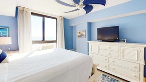 A bedroom with a bed, a TV on a dresser, a ceiling fan, and a window. - Sea Colony Ocean Fifth-Floor Condo with Hot Tub, Pool, & Basketball (Bethany Beach)