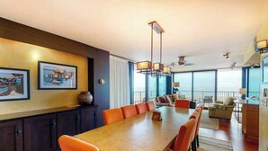A modern hotel room with a dining area, large windows, and a view of the city. - Sea Colony 3rd floor condo w/ shared sauna, gym, pool & ocean view (Bethany Beach)