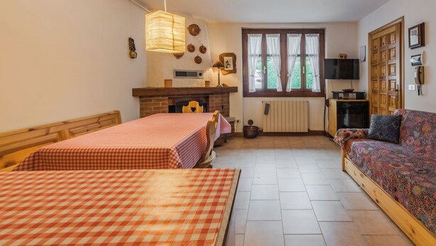 Una habitación acogedora con una cama, un sofá, una chimenea, un televisor y una ventana con cortinas.