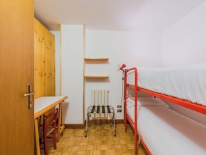 Ein kleiner, kompakter Raum mit Etagenbett, Schreibtisch und Stuhl.