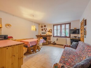 Un salon confortable avec un canapé, une table à manger et des chaises, une cheminée et un téléviseur.