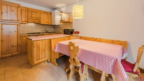 Una cocina con armarios de madera, una estufa y una mesa de comedor con mantel a cuadros.