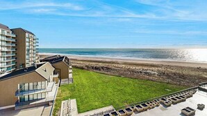 Um hotel à beira-mar com vista para o oceano, área gramada e estacionamento.