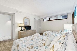 Une chambre d’hôtel avec deux lits, une télévision, une commode et une fenêtre avec des stores.