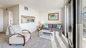 Uma sala de estar com sofá, poltrona, mesa de centro e um quadro na parede.