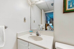Une salle de bain avec un lavabo, un miroir, un porte-serviettes et un tableau encadré au mur.