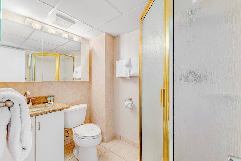 Un baño con inodoro, lavamanos, espejo y toallero.