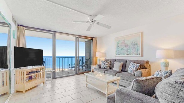 A living room with a television, sofa, coffee table, and a balcony with a view of the sea. - Sea Colony Ocean 8th floor condo w/ pool, free WiFi, & basketball court (Bethany Beach)