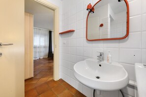 Ein Badezimmer mit Waschbecken, Spiegel und rotem Handtuchhalter.
