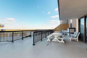Ein Balkon mit Gartenmöbeln, einem Geländer und Blick auf den Strand.