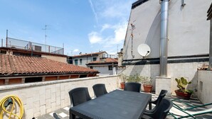 A rooftop patio with a table and chairs, potted plants, and a hose. - ‘Casa Dolce La Terrazza’ Apartment with Wi-Fi and Air Conditioning (Verona)