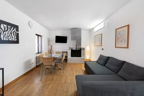 Una sala de estar moderna con un sofá, una mesa de comedor, sillas, una chimenea y obras de arte en las paredes.