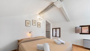 A bedroom with a large bed, two rolled towels, a light fixture, framed pictures, and a radiator. - ‘Casa Dolce La Terrazza’ Apartment with Wi-Fi and Air Conditioning (Verona)