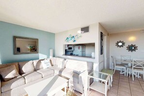 A living room with a sofa, coffee table, and dining area with chairs and a table. - Sea Colony Ocean 1st floor condo w/ basketball court, tennis court, & WiFi (Bethany Beach)