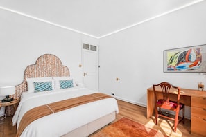 Un dormitorio con cama, escritorio y silla.
