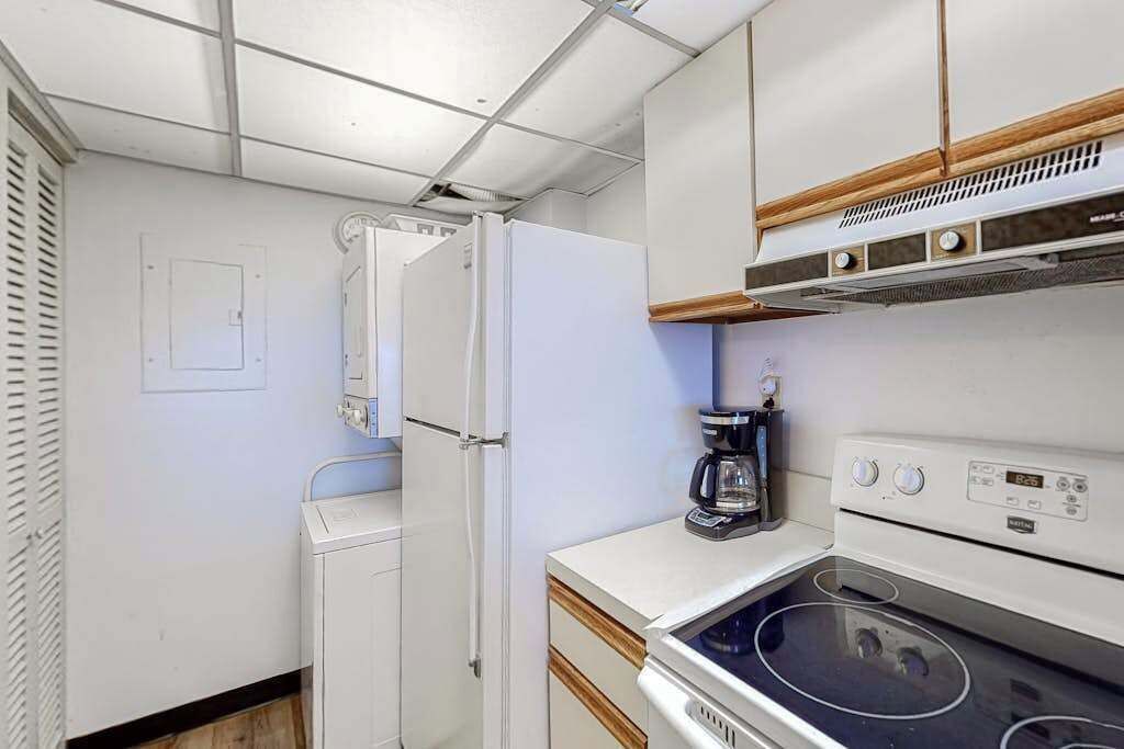 A compact kitchen with a refrigerator, stove, and coffee maker.