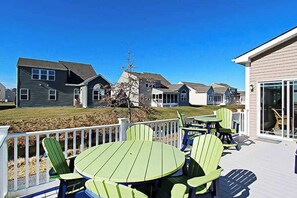 A deck with green Adirondack chairs and a table, surrounded by houses with a white fence. - Swann Cove dog-friendly house w/ balcony, gas fireplace, and shared pool (Selbyville)