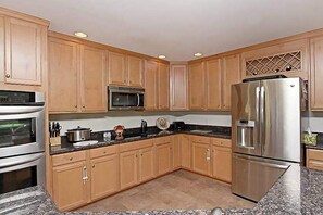 A kitchen with wooden cabinets, stainless steel appliances, granite countertops, and a built-in microwave. - Swann Cove dog-friendly house w/ balcony, gas fireplace, and shared pool (Selbyville)