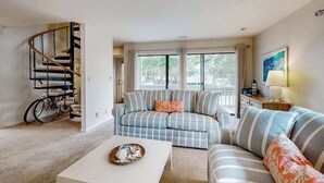 Un salon avec un canapé, une table basse, un escalier et un vélo.