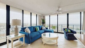 A spacious balcony with a blue sofa, a round white table, and a chair. - Sea Colony 6th floor condo w/ balcony, shared tennis court & partial ocean view (Bethany Beach)